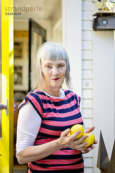 Ältere kaukasische Frau hält Zitronen im Freien