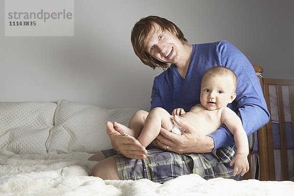 Vater hält Baby im Bett