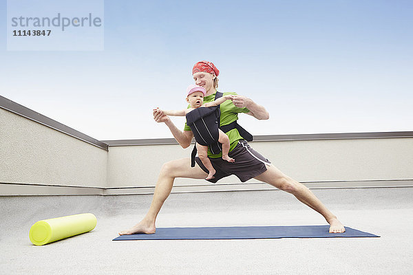 Vater übt Yoga und hält Baby