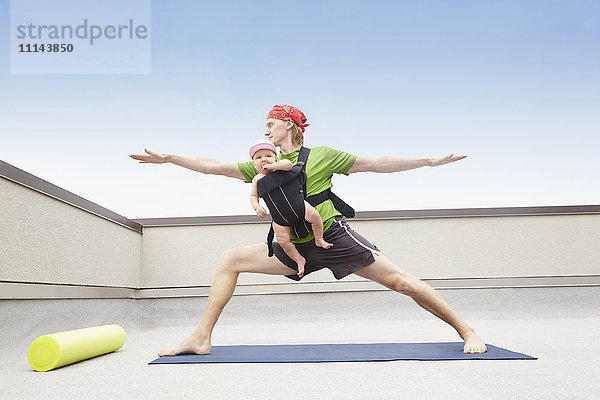 Vater übt Yoga und hält Baby