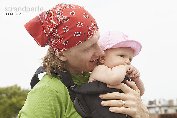 Vater trägt Baby im Freien