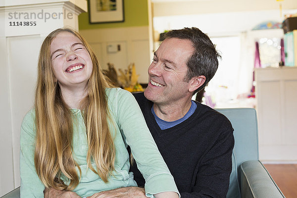 Kaukasischer Vater und Tochter lachen im Wohnzimmer