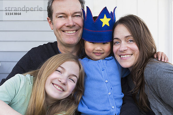 Familie lächelnd zusammen vor dem Haus