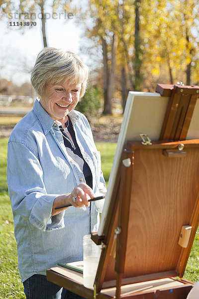 Ältere Frau malt im Freien