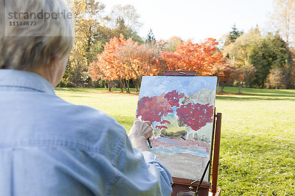 Ältere Frau malt im Freien