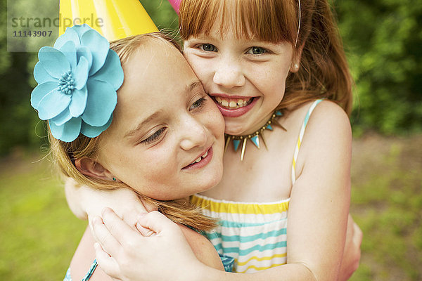 Mädchen umarmen sich auf einer Geburtstagsfeier im Freien