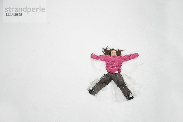 Kaukasisches Mädchen macht Schneeengel