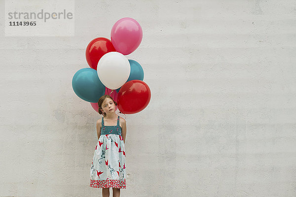 Kaukasisches Mädchen hält ein Bündel Luftballons
