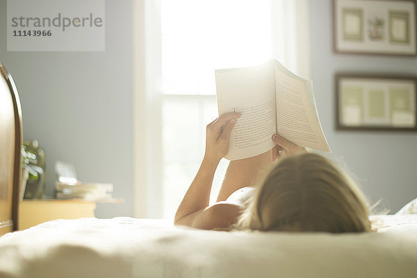 Kaukasisches Mädchen liest Buch auf dem Bett