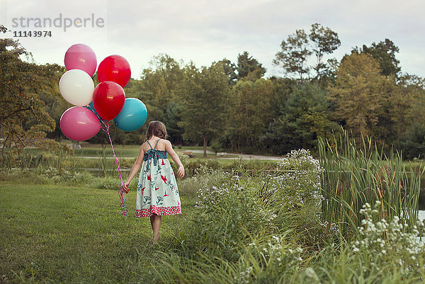 Kaukasisches Mädchen trägt Luftballons in einem ländlichen Feld
