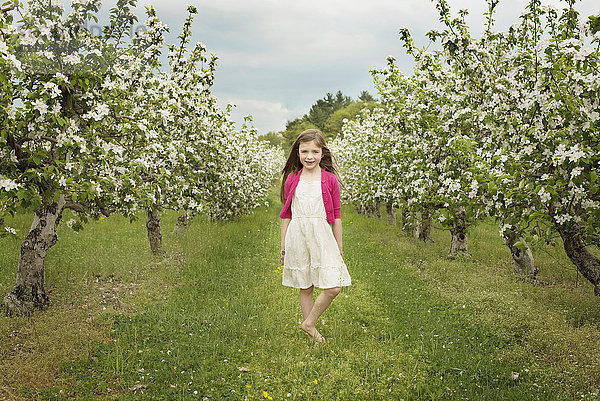 Kaukasisches Mädchen geht in blühendem Obstgarten