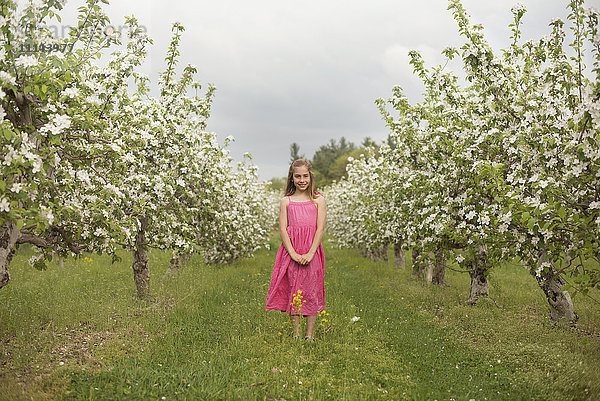 Kaukasisches Mädchen in blühendem Obstgarten stehend