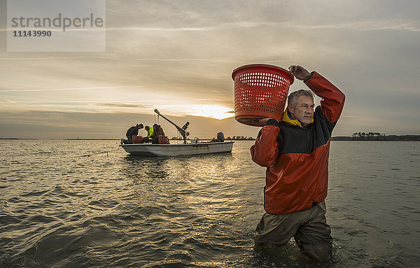 Kaukasischer Fischer trägt Korb im Wasser