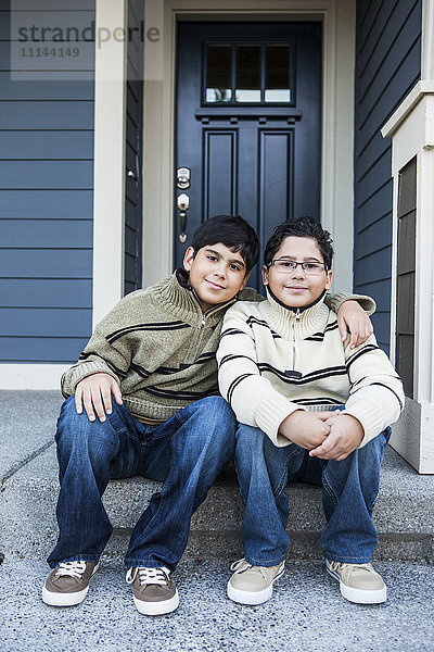 Hispanische Jungen umarmen sich auf der Eingangstreppe