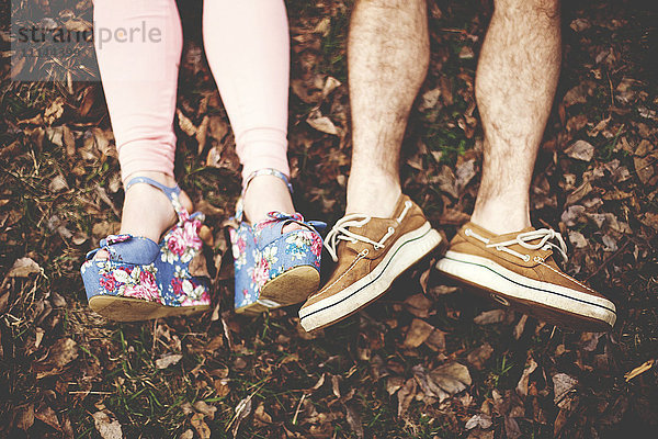 Nahaufnahme der Schuhe eines Paares  das im Herbstlaub liegt