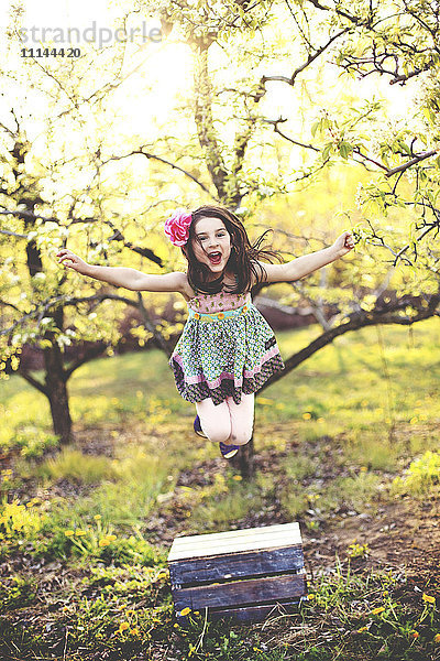 Mädchen springt vor Freude im Obstgarten