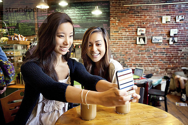 Frauen nehmen Selfie mit Handy im Café Tisch