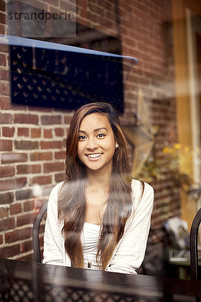 Lächelnde Frau hinter dem Fenster eines Cafés