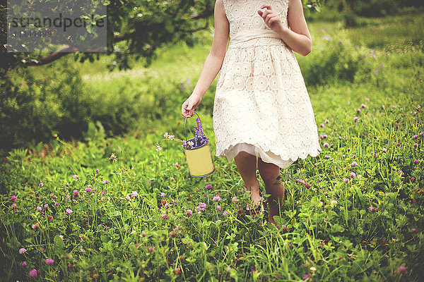 Mädchen pflückt Blumen auf einem ländlichen Feld