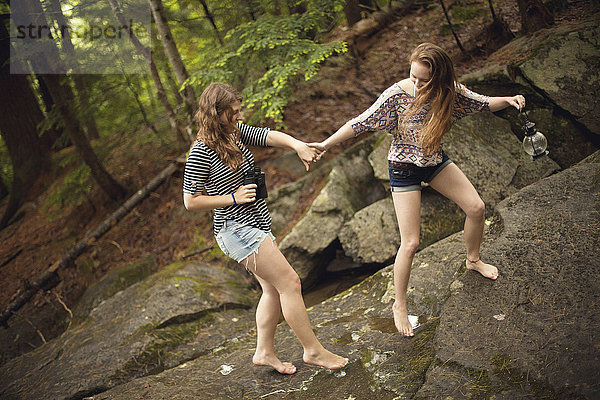 Mädchen gehen barfuß auf Felsen im Wald