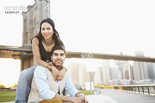 Indisches Paar lächelnd bei Brücke  New York  New York  Vereinigte Staaten