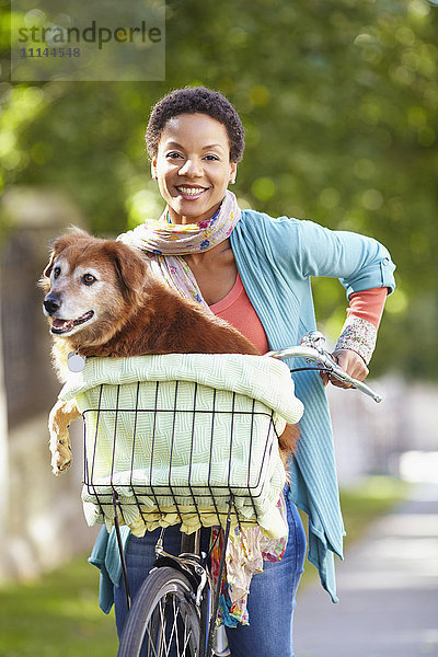 Schwarze Frau mit Hund im Fahrradkorb