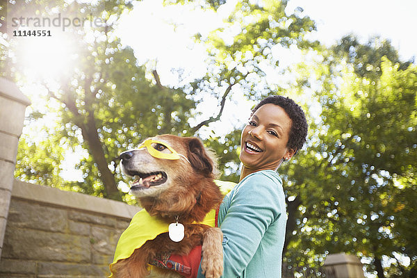 Schwarze Frau mit kostümiertem Hund im Park