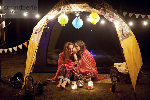 Mädchen flüstern nachts im Campingzelt