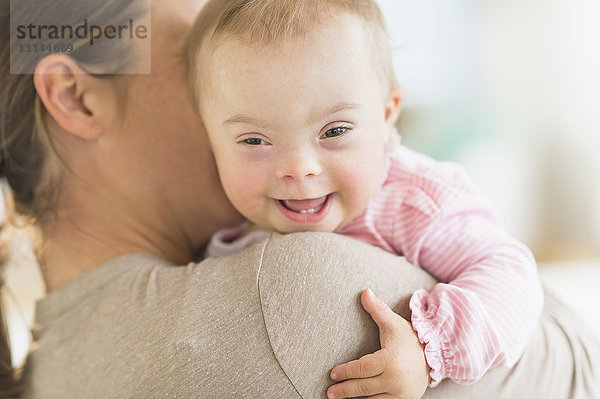 Kaukasische Mutter hält ihr kleines Mädchen mit Down-Syndrom