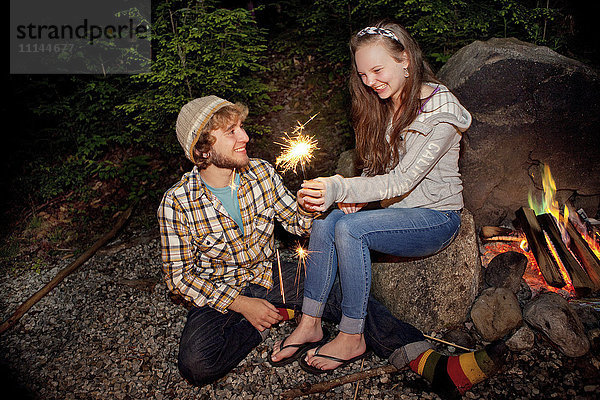 Paar spielt mit Wunderkerze am Lagerfeuer