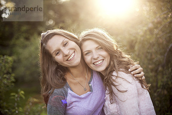 Lächelnde Frauen umarmen sich in einem ländlichen Feld