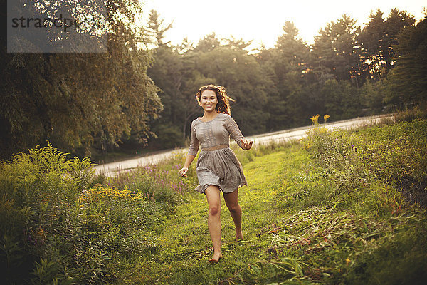 Lächelnde Frau läuft in einem ländlichen Feld