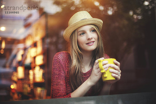 Mädchen trinkt Kaffee im Café am Fenster
