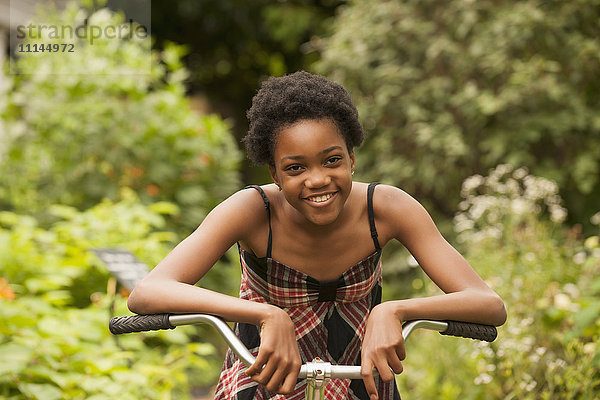 Afroamerikanisches Mädchen sitzt auf einem Fahrrad im Hinterhof