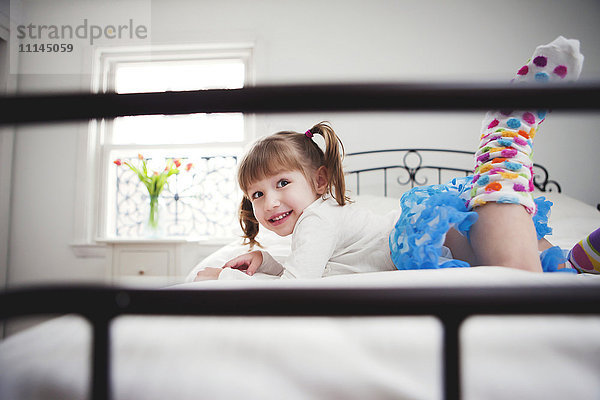 Lächelndes Mädchen spielt auf dem Bett