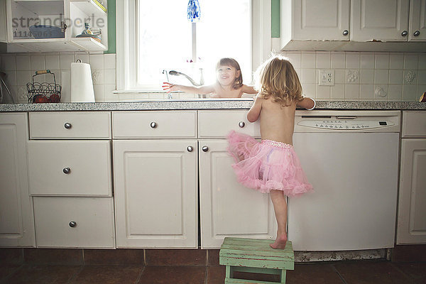 Schwestern spielen an der Küchenspüle