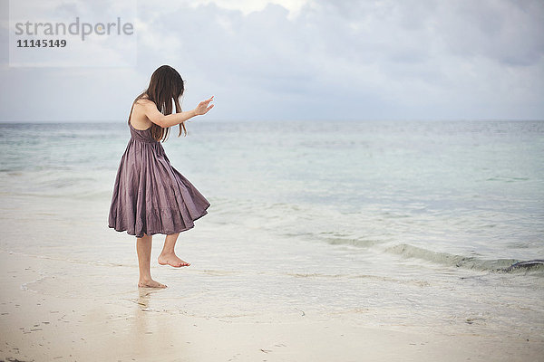 Mädchen tanzt in den Wellen am Strand