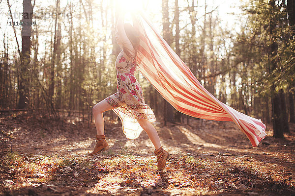 Hispanische Frau läuft mit Schal im Wald