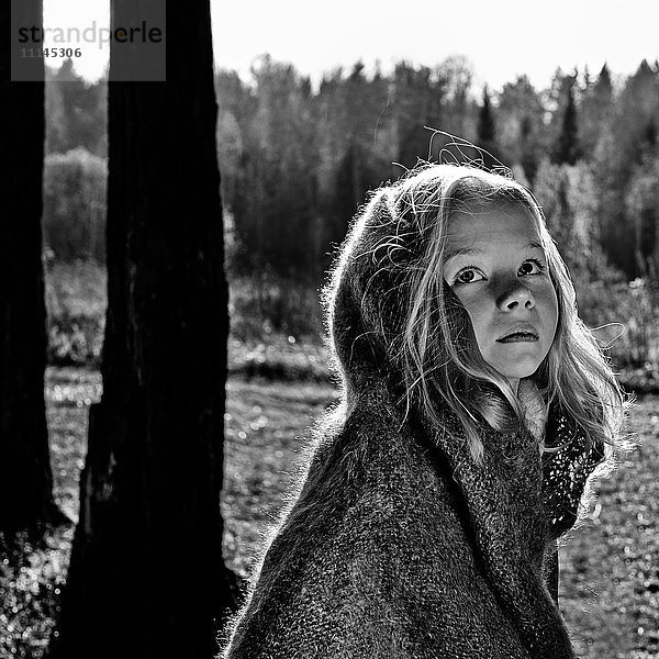 Kaukasisches Mädchen eingewickelt in eine Decke im Wald