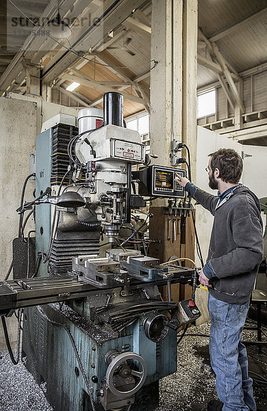 Kaukasischer Mann bei der Arbeit mit Maschinen in einer Metallwerkstatt