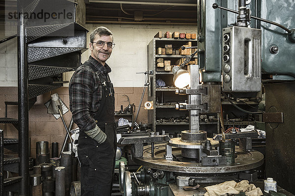 Porträt eines lächelnden kaukasischen Mannes in einer Metallwerkstatt