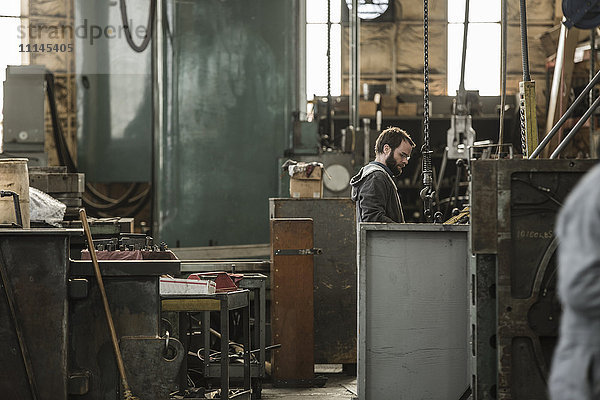 Kaukasischer Mann bei der Arbeit mit Maschinen in einer Werkstatt