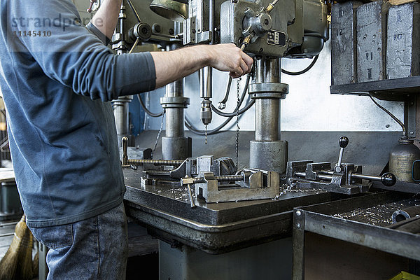 Kaukasischer Mann mit Bohrmaschine in einer Werkstatt