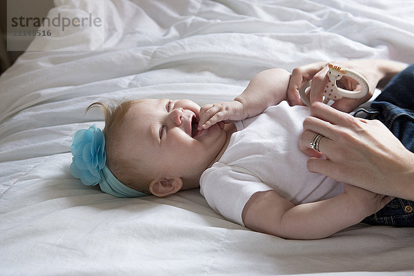 Nahaufnahme von Mutter kitzeln Baby Mädchen auf dem Bett