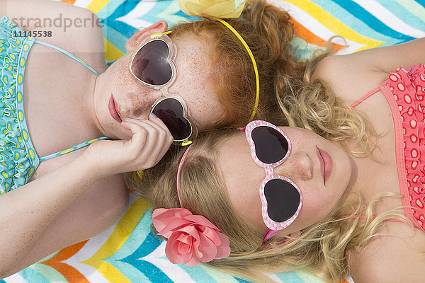 Kaukasische Mädchen beim Sonnenbaden mit herzförmigen Sonnenbrillen