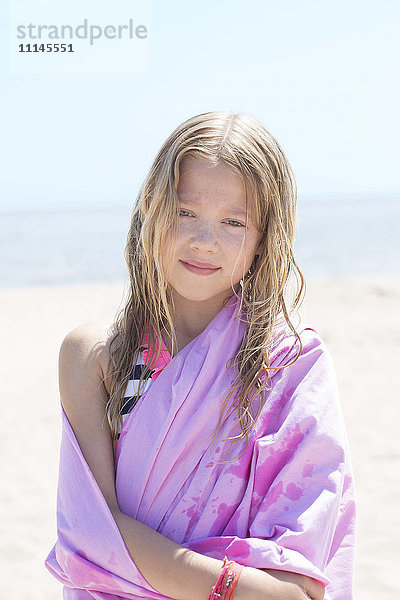 Kaukasisches Mädchen  eingewickelt in ein Handtuch am Strand