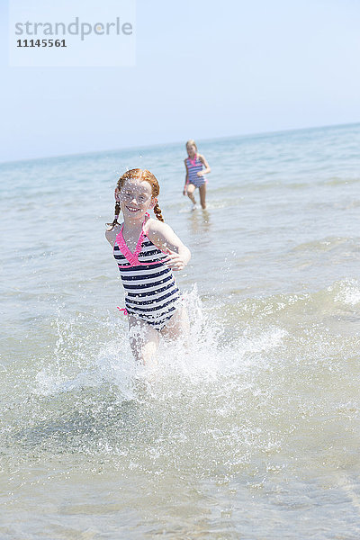 Kaukasisches Mädchen plantscht in den Wellen am Strand