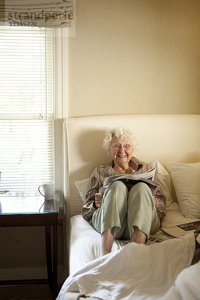 Ältere kaukasische Frau liest Zeitung im Bett
