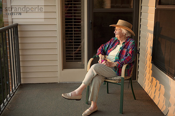 Ältere kaukasische Frau sitzt auf Veranda