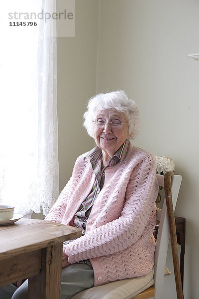 Ältere Frau lächelt am Tisch